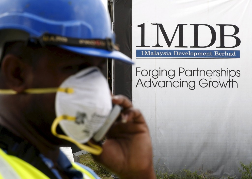 A construction worker talks on the phone in front of a 1Malaysia Development Berhad (1MDB) billboard at the Tun Razak Exchange development in Kuala Lumpur, Malaysia, in this February 3, 2016 file photo. Credit: Reuters/Olivia Harris/Files