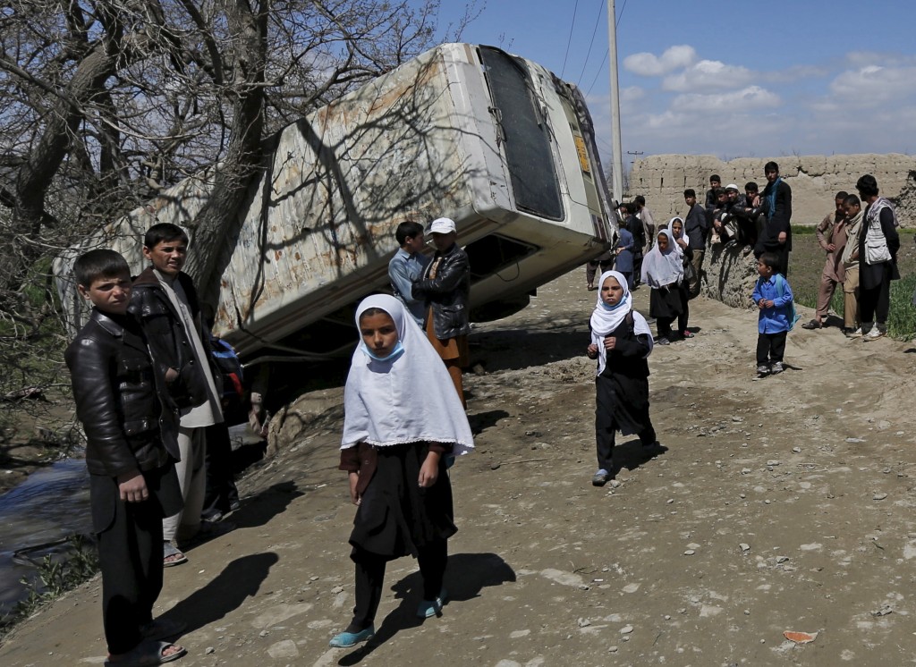 Schoolgirls walk past a damaged mini-bus after it was hit by a bomb blast in the Bagrami district of Kabul, Afghanistan April 11, 2016. Credit: REUTERS/Mohammad Ismail