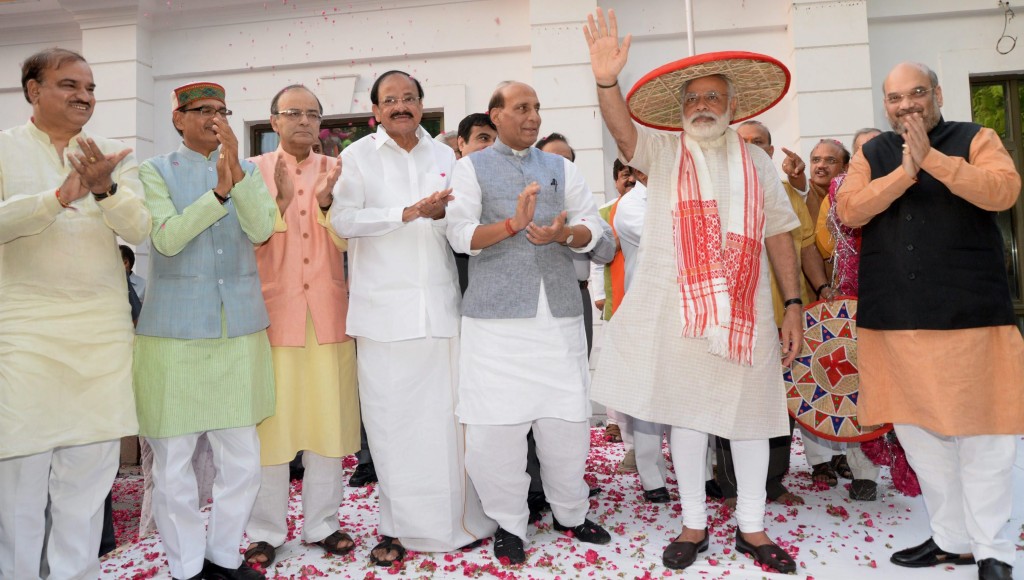 Prime Minister Narendra Modi waves at BJP workers after being presented an Assamese japi and gamosa to mark the party's victory in the Assam assembly polls on Thursday. Credit: PTI/Vijay Verma