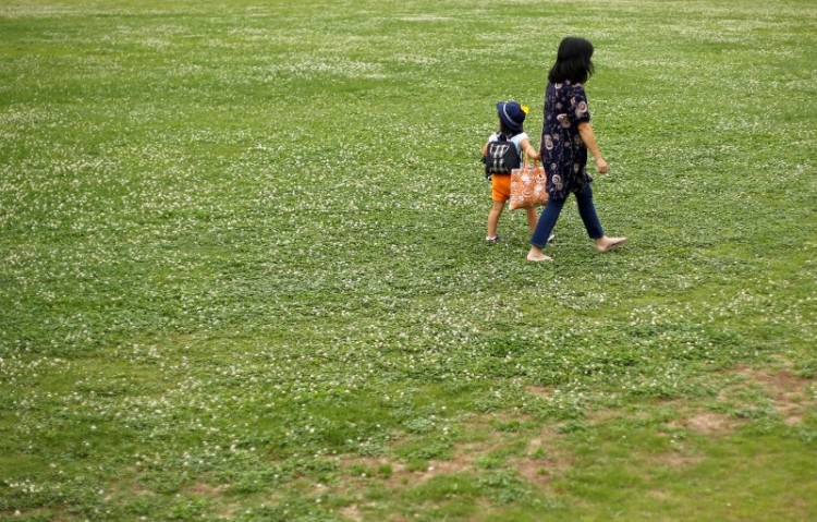 Foster mother Asako Yoshinari and her foster child walk at a park near her home in Inzai, Chiba prefecture, Japan, June 24, 2016. Picture taken June 24, 2016. Credit: Reuters/Toru Hanai