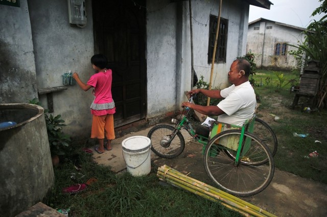 Former soldier Than Htike, 50, who lost his leg in the war in Kayah state after he stepped on a landmine in 2007, waits for his daughter to open the door of their house outside Yangon, Myanmar June 3, 2016. Credit: Reuters/Soe Zeya Tun