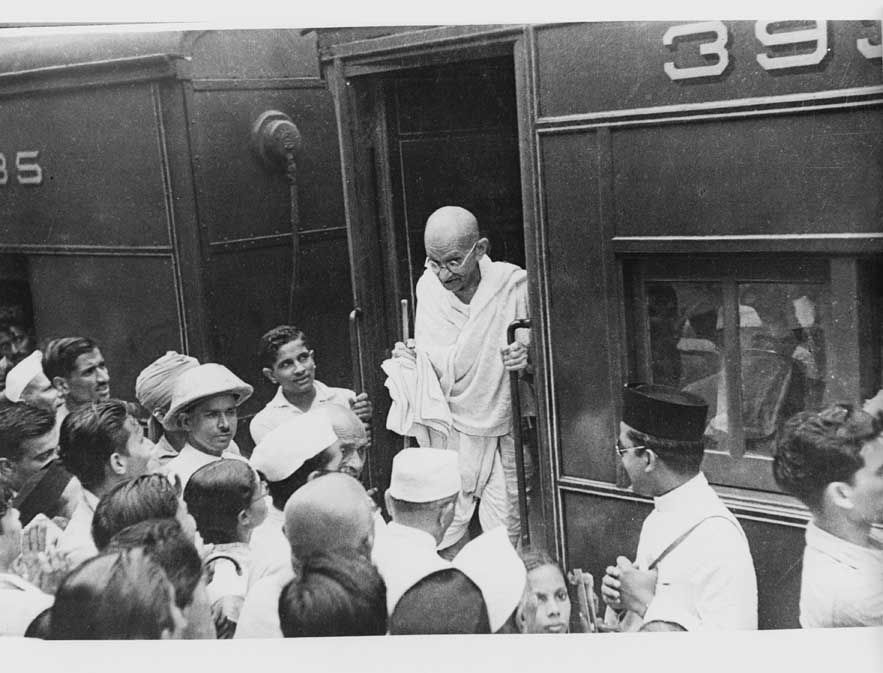 A crowd greets Gandhi as he alights at a station. Credit: Wikimedia Commons