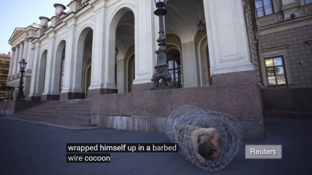 Screenshot of Petr Pavlensky cocooned in barbed wire. Credit: Youtube/ Reuters