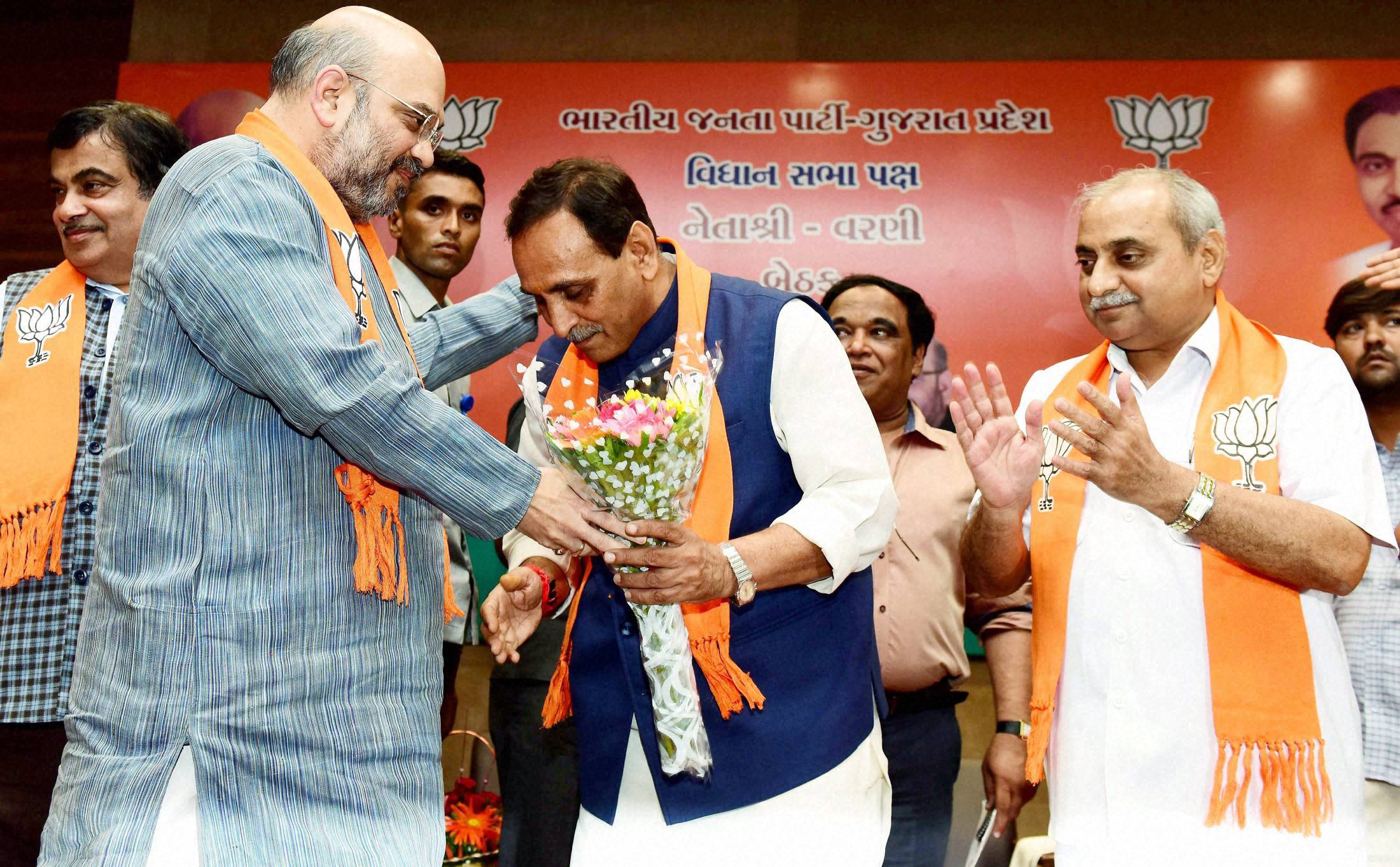 Gujarat's new chief minister Vijay Rupani seeks the blessings of BJP president Amit Shah as deputy CM Nitin Patel looks on, after their meeting at Gujarat BJP headquarters at Gandhinagar on Friday. Credit: PTI Photo