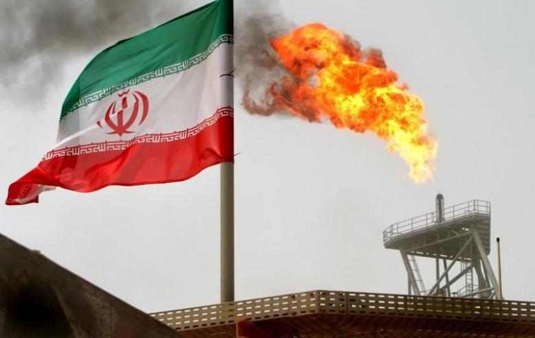 A gas flare on an oil production platform is seen alongside an Iranian flag in the Gulf July 25, 2005. Credit: Reuters/Raheb Homavandi/File Photo