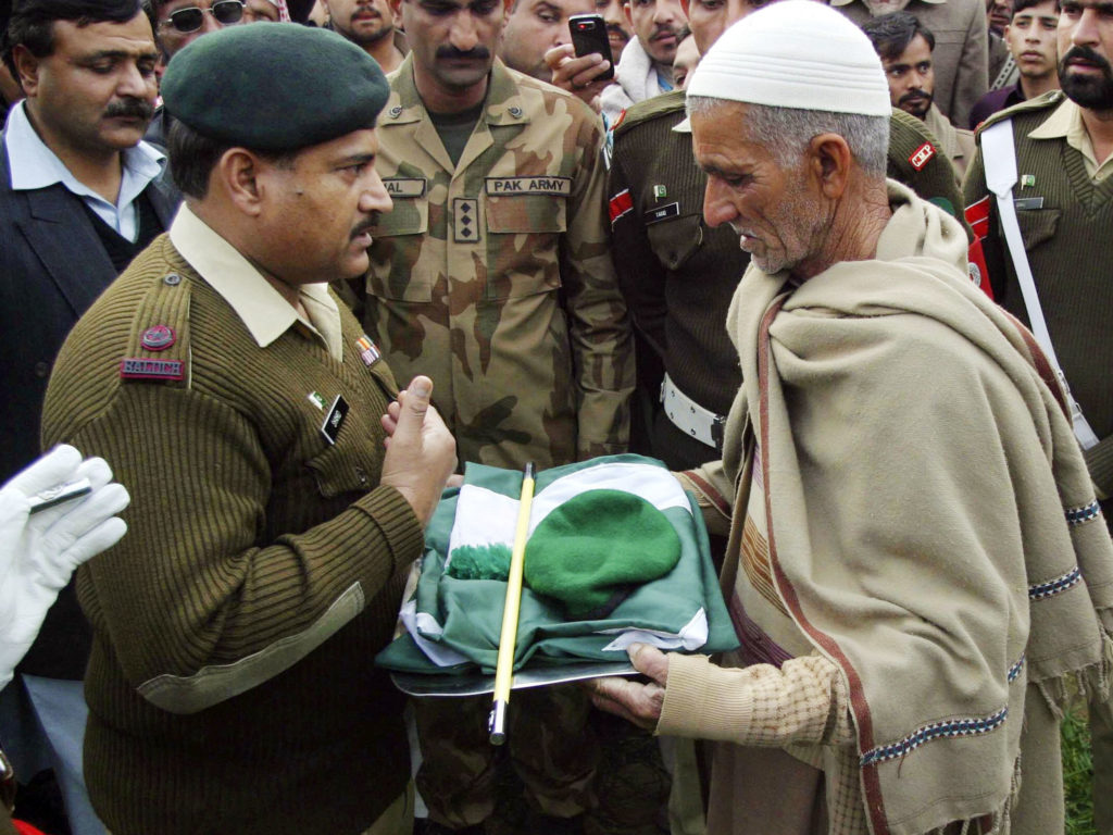 A military official hands over a Pakistan military cap, stick and national flag to the father of Pakistani soldier Muhammad Akhlaq, whom the Pakistan military said was killed by Indian soldiers while crossing into the Indian side of Kashmir. Credit: Reuters