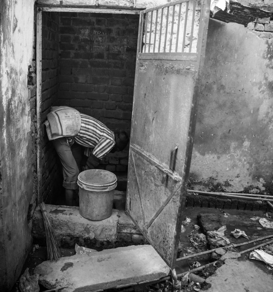 A man cleaning a dry latrine. Credit: Sharada Prasad CS/Flickr CC BY 2.0