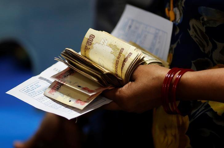 A woman holds 500 and 1000 Indian rupee banknotes as she stands in a queue to deposit her money inside a bank in the northern city of Kanpur, India, November 10, 2016. Credit: Adnan Abidi/Reuters/Files