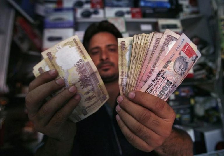 A shopkeeper poses for a picture as he counts rupees at his shop in Jammu. Credit: Reuters/Files
