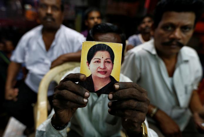 A supporter of J. Jayalalithaa holds her photo at the AIADMK party office in Mumbai, India, December 5, 2016. Credit: Reuters/Danish Siddiqui