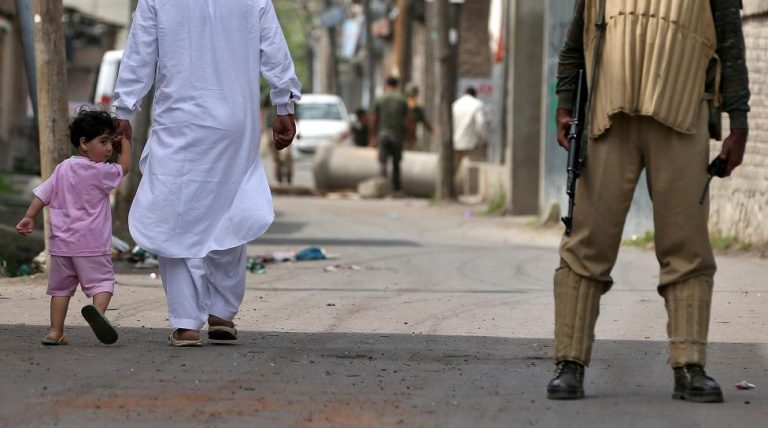 A boy looks back at a member of the security forces in Srinagar as the city remains under curfew following weeks of violence in Kashmir August 19, 2016. Credit: Reuters/Cathal McNaughton