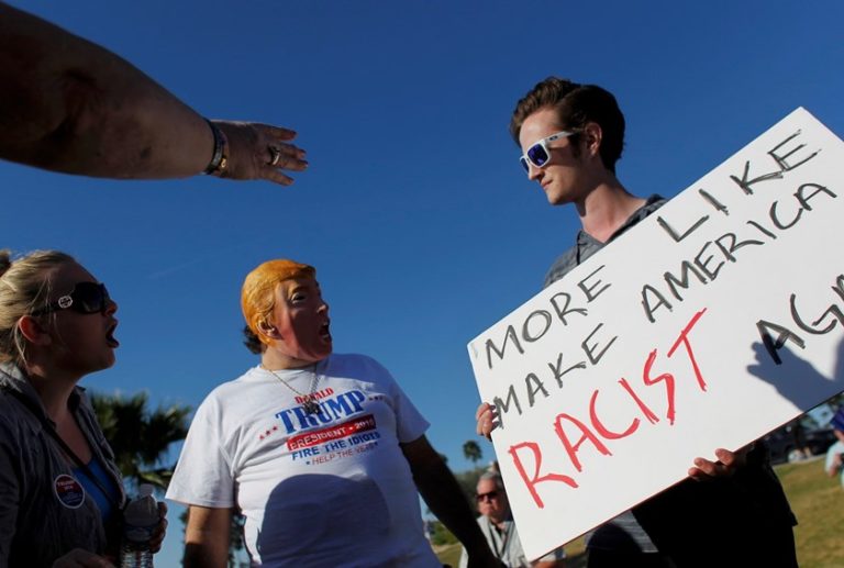 Supporters (L) of Republican U.S. presidential candidate Donald Trump point and scream at an anti-Trump demonstrator (R) holding a sign reading