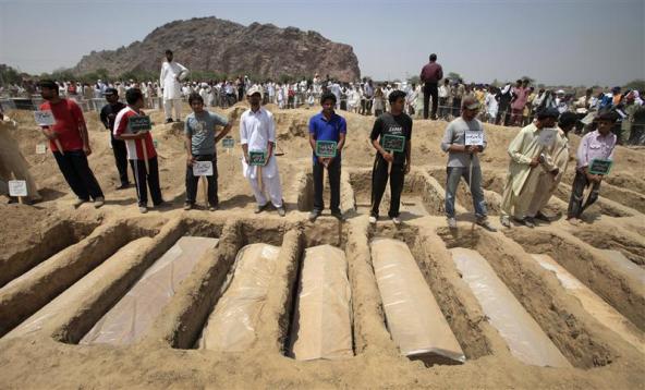 Ahmadis stand over graves of victims of an attack on one of their mosques, in Rabwah, May 29, 2010. Credit: Reuters/Files
