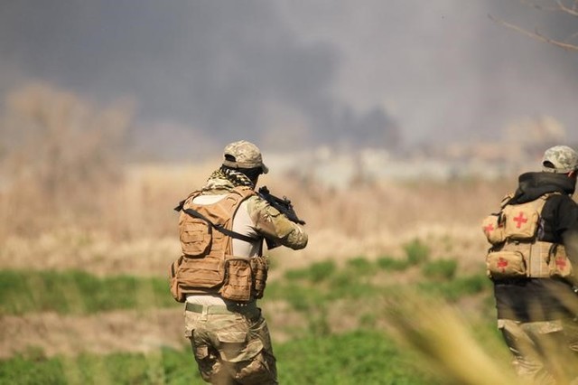 Rapid Response forces members cross farm land during a battle with ISIS's militants south west Mosul, Iraq February 24, 2017. Credit: Reuters