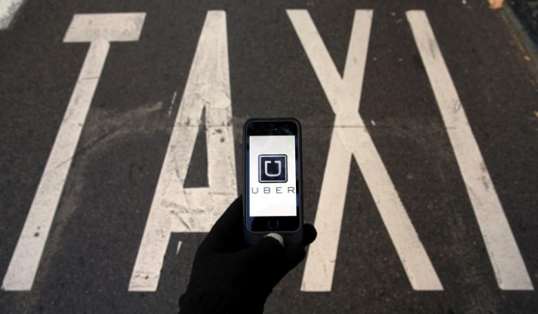 The logo of car-sharing service app Uber on a smartphone over a reserved lane for taxis in a street is seen in this photo illustration taken December 10, 2014. Credit: Reuters/Sergio Perez/Illustration/Files