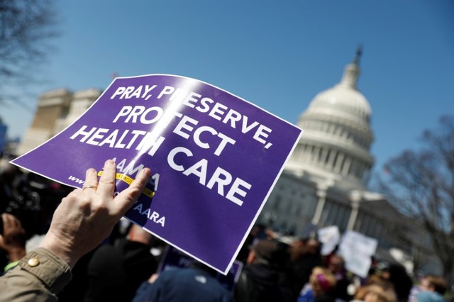 Demonstrators hold signs during a protest against the repeal of the Affordable Care Act outside the Capitol Building in Washington, US, March 22, 2017. Credit: Reuters