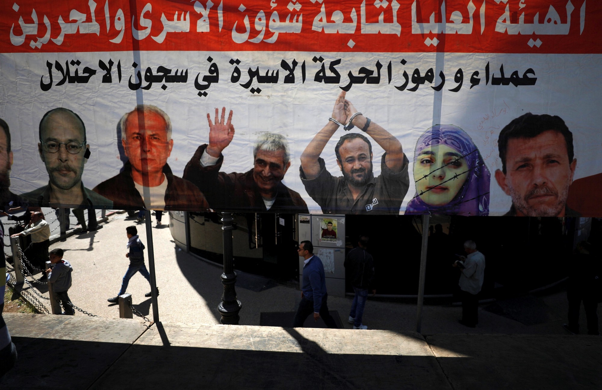 People walk past a poster depicting Palestinian prisoners held in Israeli jails, in the West Bank city of Ramallah April 17, 2017. Credit: Reuters/Mohamad Torokman