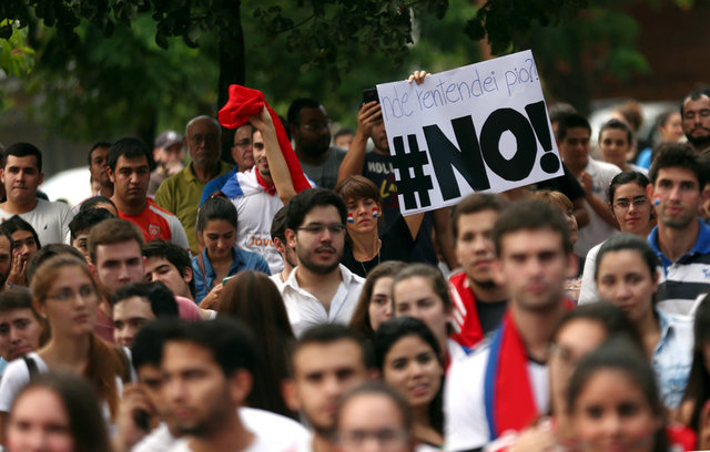 A woman holds a sign reading NO during a students' rally against a proposed amendment that would allow Paraguay's president to stand for re-election in Asuncion, Paraguay, April 2, 2017. Credit: Reuters