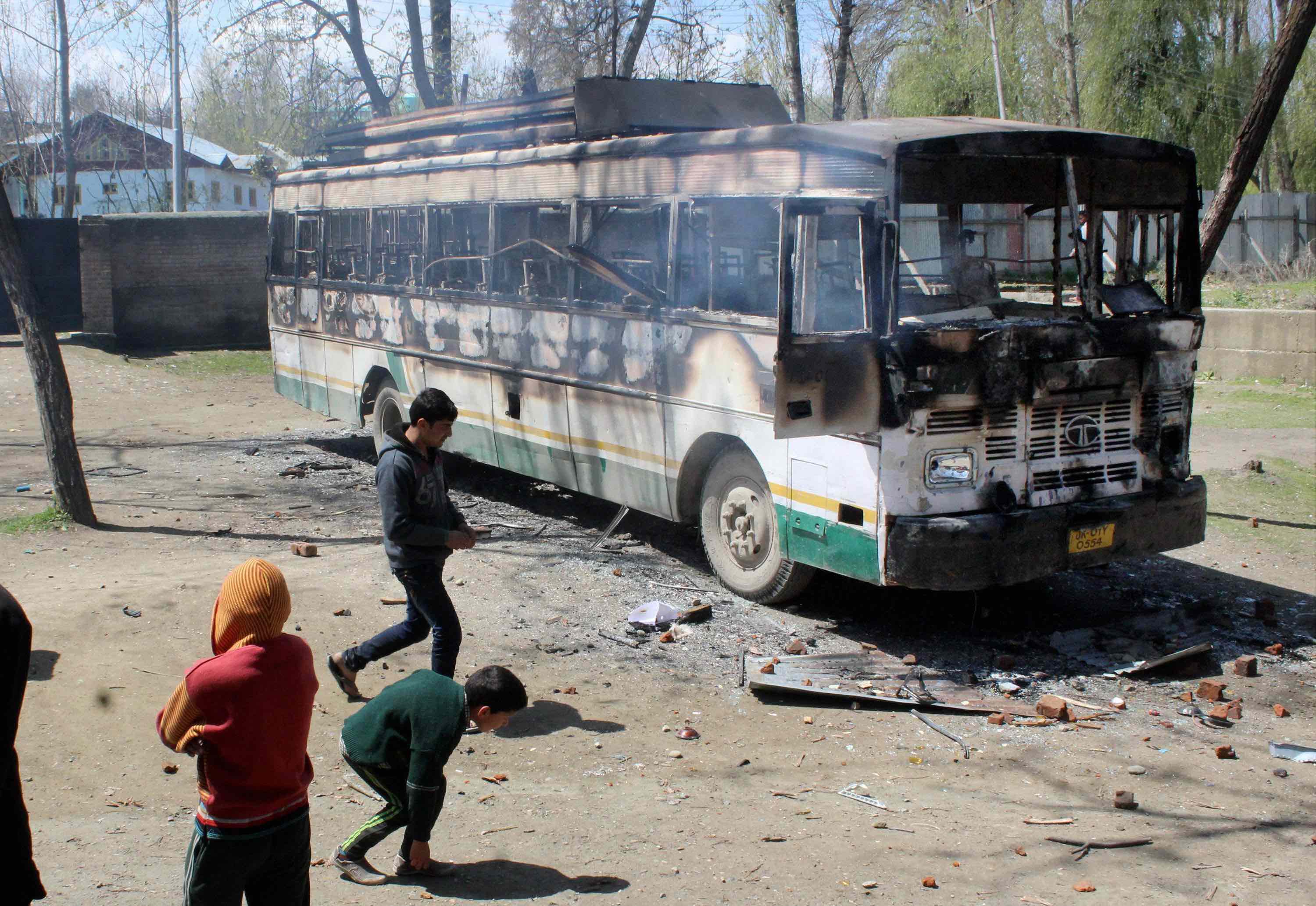 Protesters throwing stones at a burning polling staff bus after they attacked a polling station at Kanihama in Srinagar on Sunday. Credit: PTI