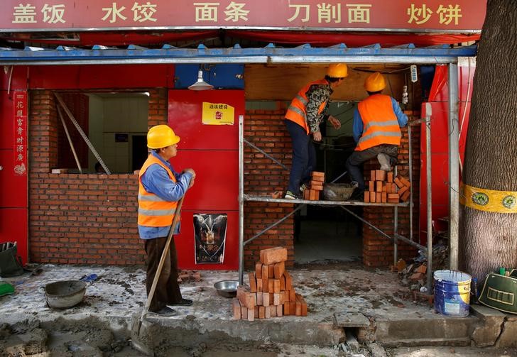 Workers build a brick wall across the front of a restaurant in a hutong alley in Beijing, China May 5, 2017. Credit: Reuters/Thomas Peter