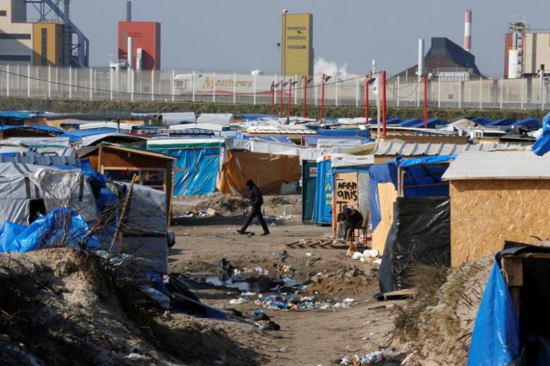 A migrant walks past makeshift shelters in the northern area on the final day of the dismantlement of the southern part of the camp called the 'Jungle