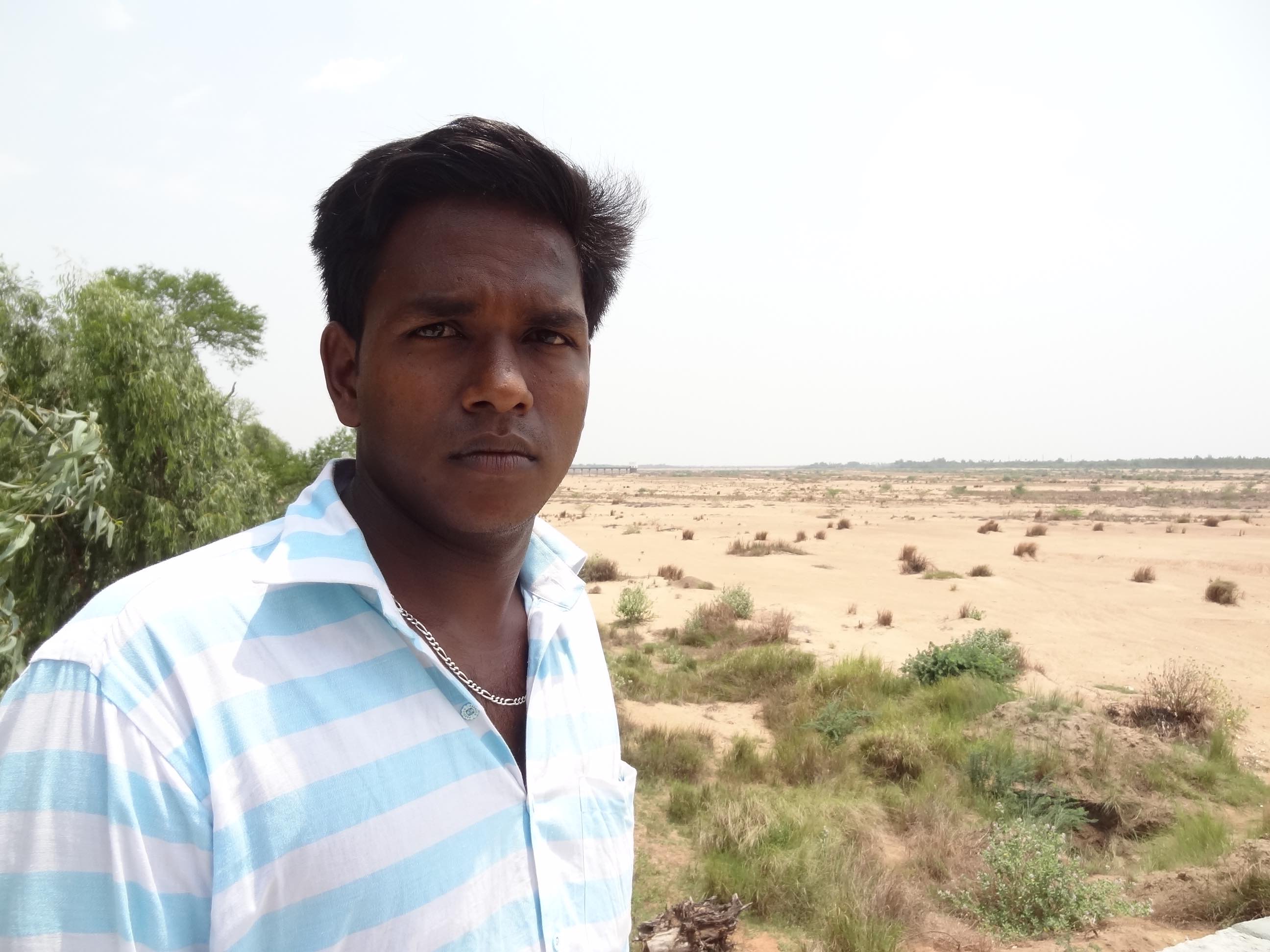 Karti, the second son of S. Selvaraju, against the backdrop of a dry Kollidam river along his village. Credit: Jaideep Hardikar
