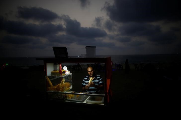 A Palestinian vendor sells snacks on a beach during a power cut as he uses battery-powered lights in Gaza City, July 12, 2017. Credit: Reuters/Mohammed Salem/Files