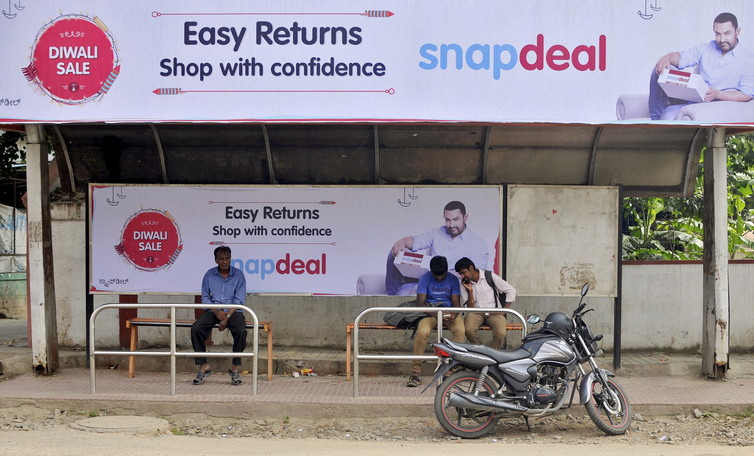 Commuters sit at a bus stop adorned with an advertisement of Indian online marketplace Snapdeal. Credit: Reuters/Abhishek Chinnappa