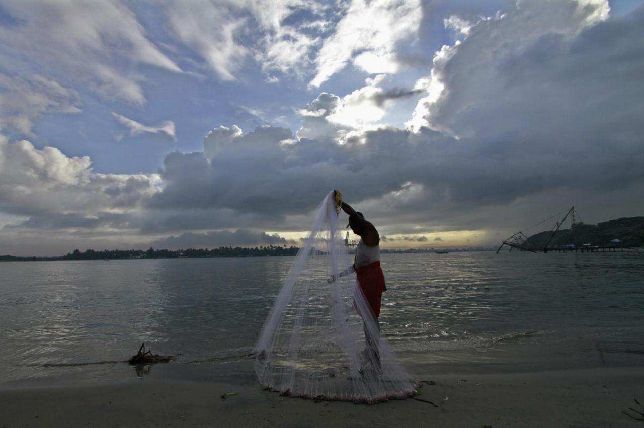 A fisherman arranges his fishing net at a beach against the backdrop of pre-monsoon clouds in Kochi June 5, 2014. Credit: Reuters/Sivaram V
