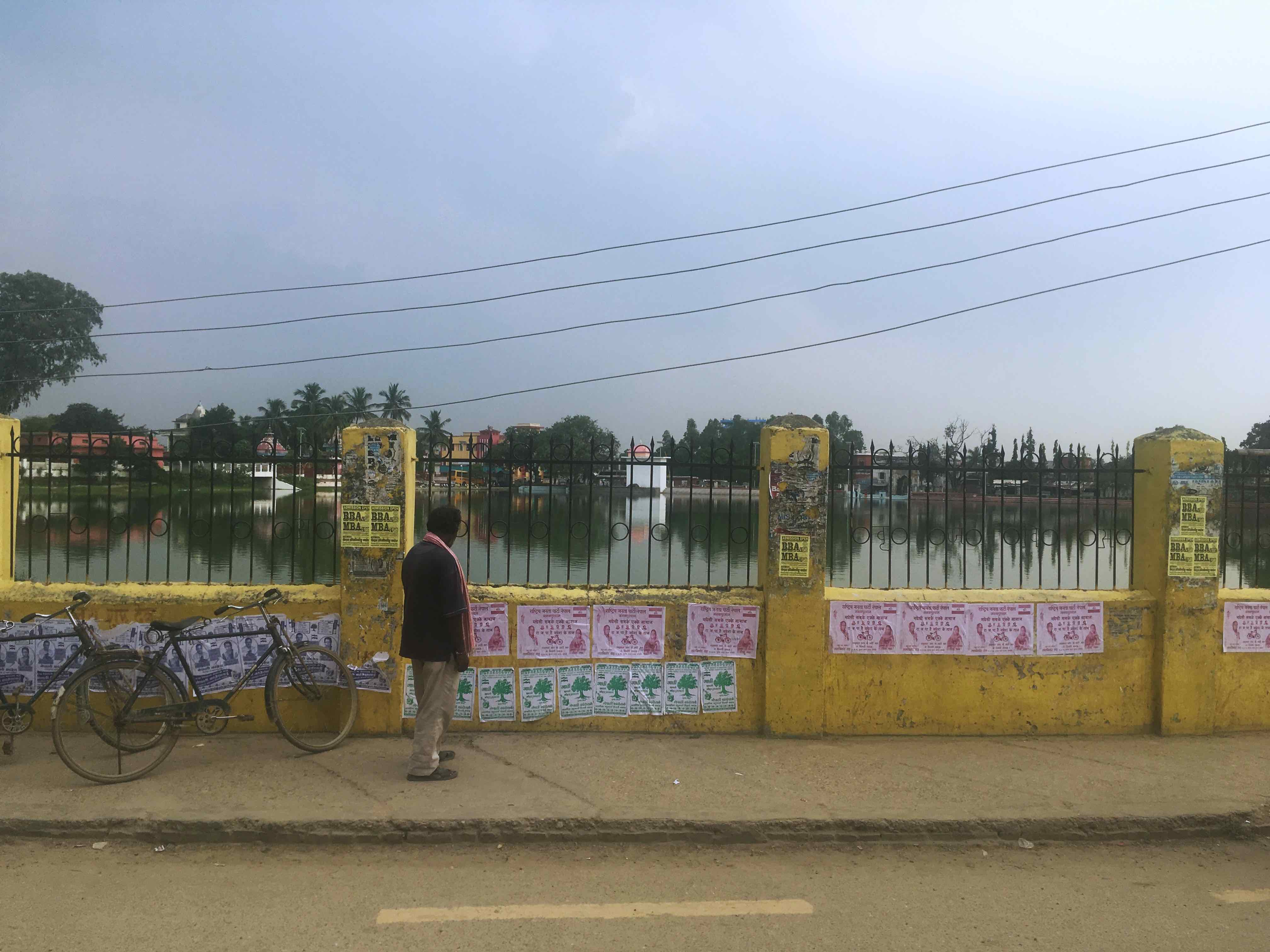 A man looks at election posters in front of Dhanus Sagar in Janakpur. Credit: Peter Gill