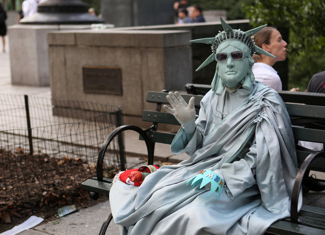 A man dressed as the Statue of Liberty waves at protesters (not pictured) marching against U.S. President Donald Trump's proposed end of the DACA program that protects immigrant children from deportation in New York City, U.S., August 30, 2017. Credit:Reuters