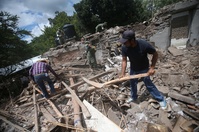 Soldiers and residents clear rubble from a destroyed house after an earthquake in San Juan Pilcaya, at the epicenter zone, Mexico, September 25, 2017. Credit: Reuters