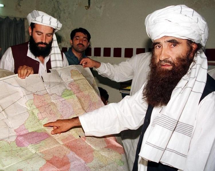 Jalaluddin Haqqani (R), the Taliban's minister for tribal affairs, points to a map of Afghanistan during a visit to Islamabad, Pakistan while his son Naziruddin (L) looks on in this October 19, 2001 file photograph. Credit: Reuters/Stringer/Files