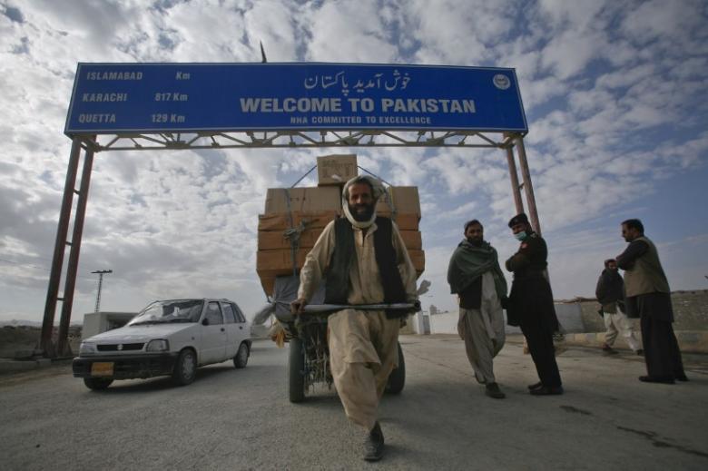A man passes a road sign while pulling supplies towards the Pakistan-Afghanistan border crossing in Chaman November 28, 2011. Credit: Reuters/Naseer Ahmed