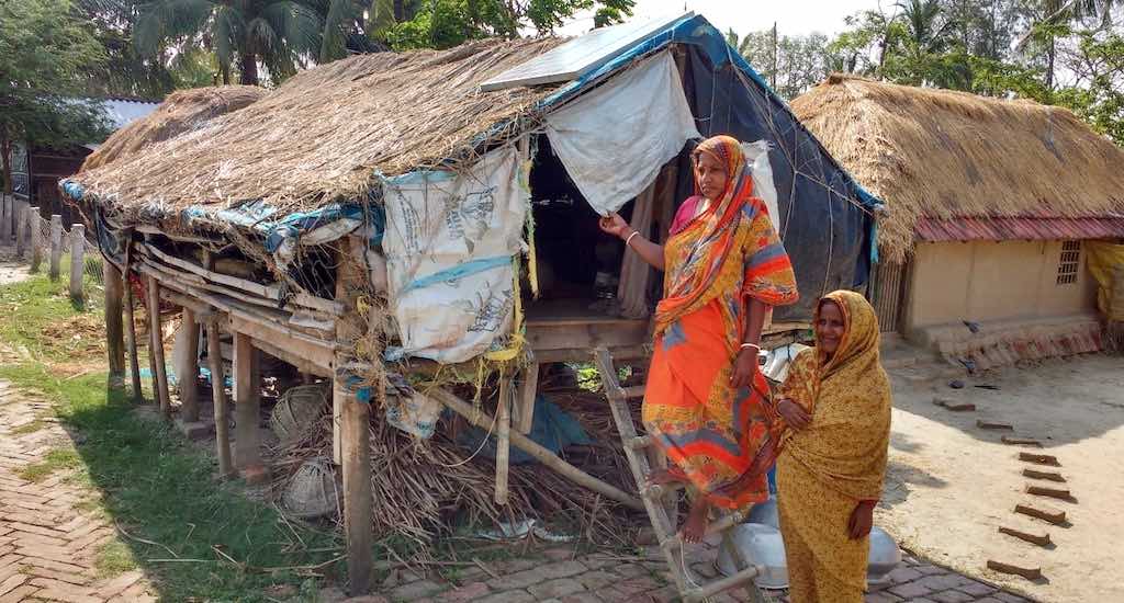 Women who remain on the island after the men migrate take shelter in a stilt house during floods.