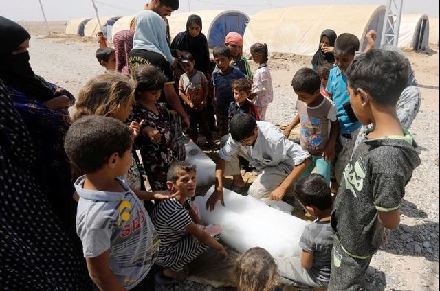 Displaced Iraqis wait to get ice in Jada camp south of Mosul, Iraq August 9, 2017. Credit: Reuters