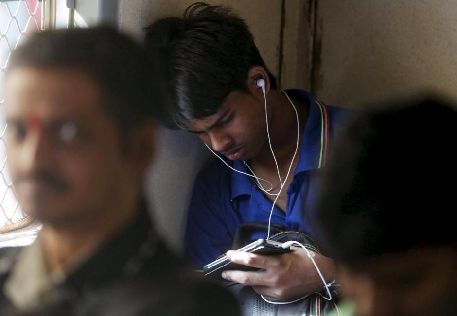 A man watches a video on his mobile phone as he commutes by a suburban train in Mumbai, India, March 31, 2016. Credit: Reuters/Shailesh Andrade