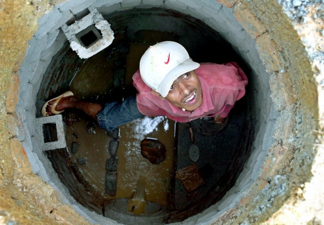 An Indian labourer looks on as he repairs a manhole in Mumbai September 14, 2005. Credit: Reuters