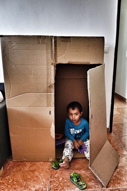 Lokman playing hide and seek in a fridge carton. While playing, he acts out he family's escape from Aleppo, though he was to young to understand. Credit: Shome Basu