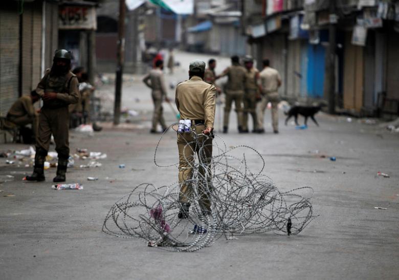 A policeman pulls concertina wire to lay a barricade on a road in Srinagar. Credit: Reuters/Danish Ismail 