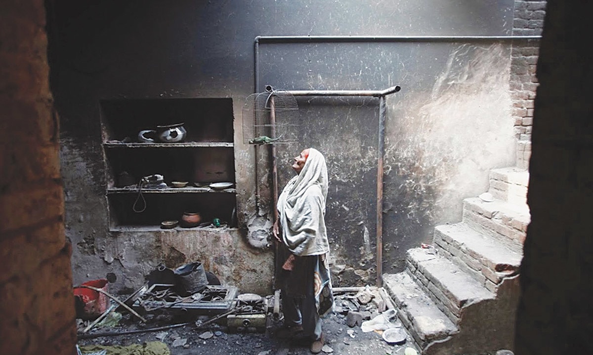 An elderly woman looks at her pet bird, which died during the mob attack on Joseph Colony in March 2013. Credit: Reuters