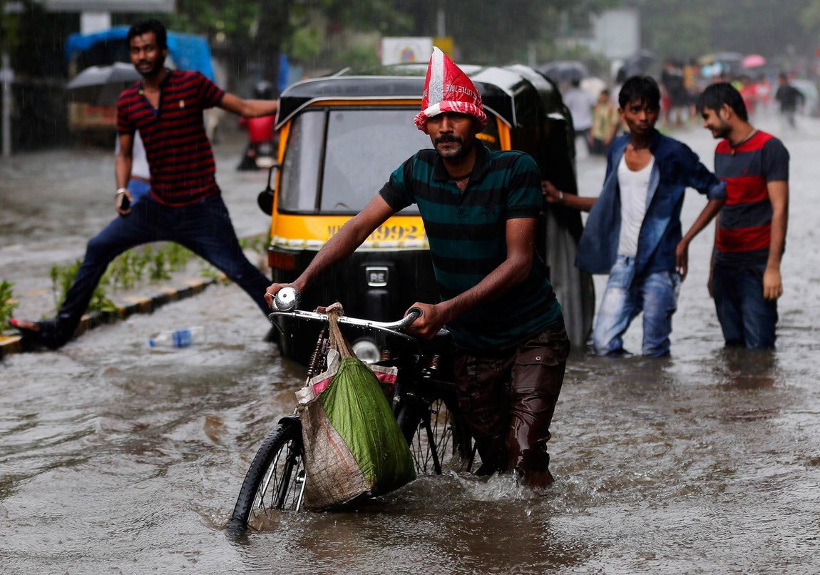 A man pushes his bicycle on a flooded road during heavy rains in Mumbai. Credit: Reuters/Shailesh Andrade