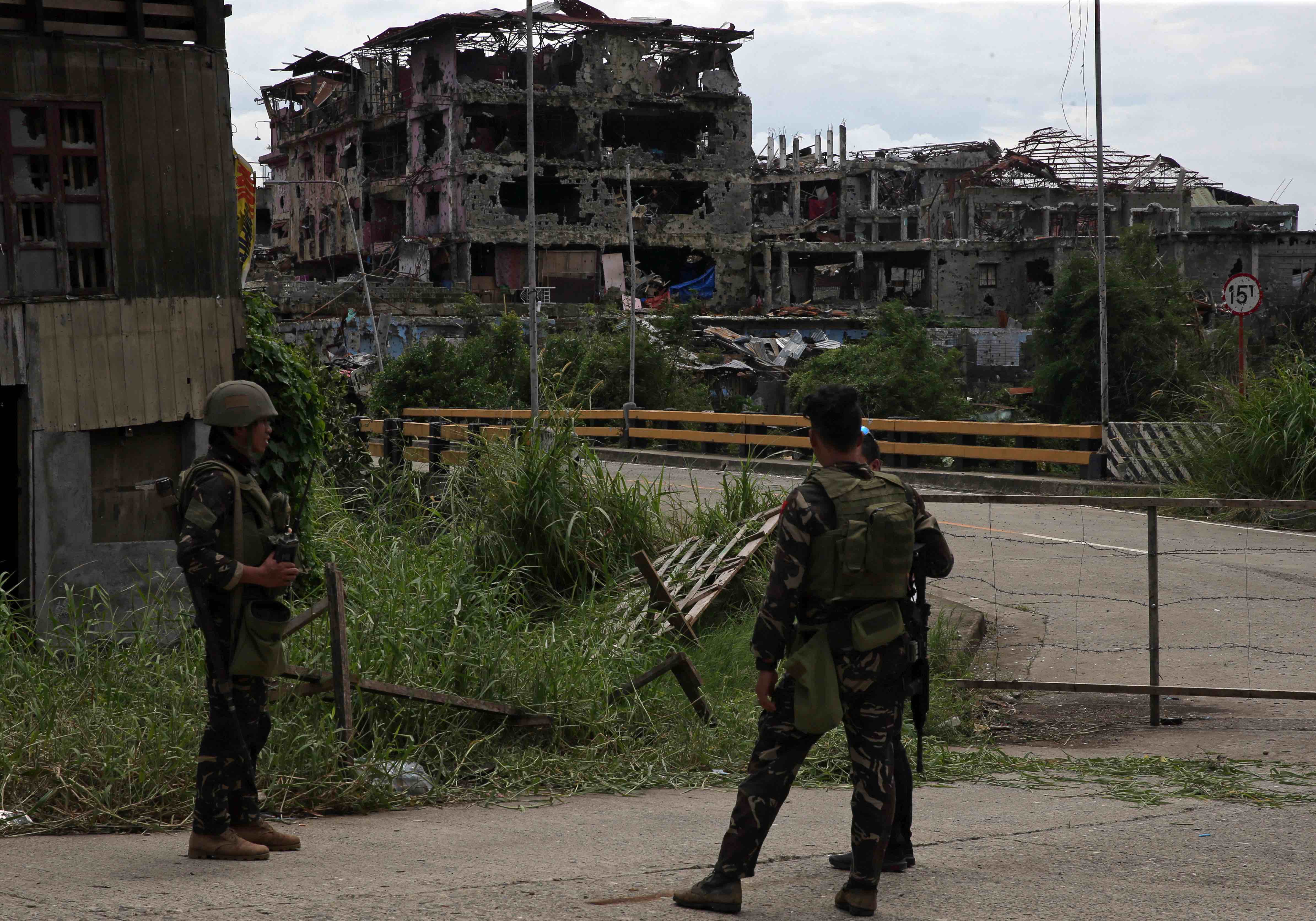 Soldiers stand on guard and look at damaged buildings and houses after government troops cleared the area from pro-Islamic State militant groups inside the war-torn area in Saduc proper, Marawi city, southern Philippines October 22, 2017. Credit: Reuters/Romeo Ranoco