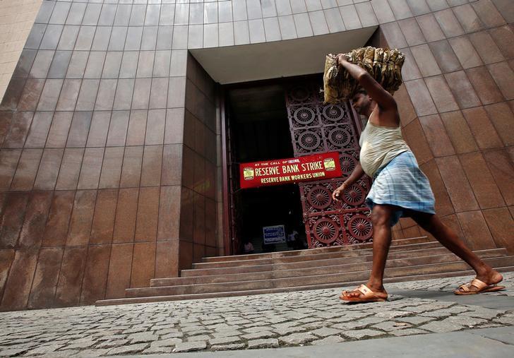 A labourer carrying dry leaves walks past a Reserve Bank of India (RBI) building during a nationwide strike in Kolkata, India September 2, 2016. Credit: Reuters/Rupak De Chowdhuri/File Photo