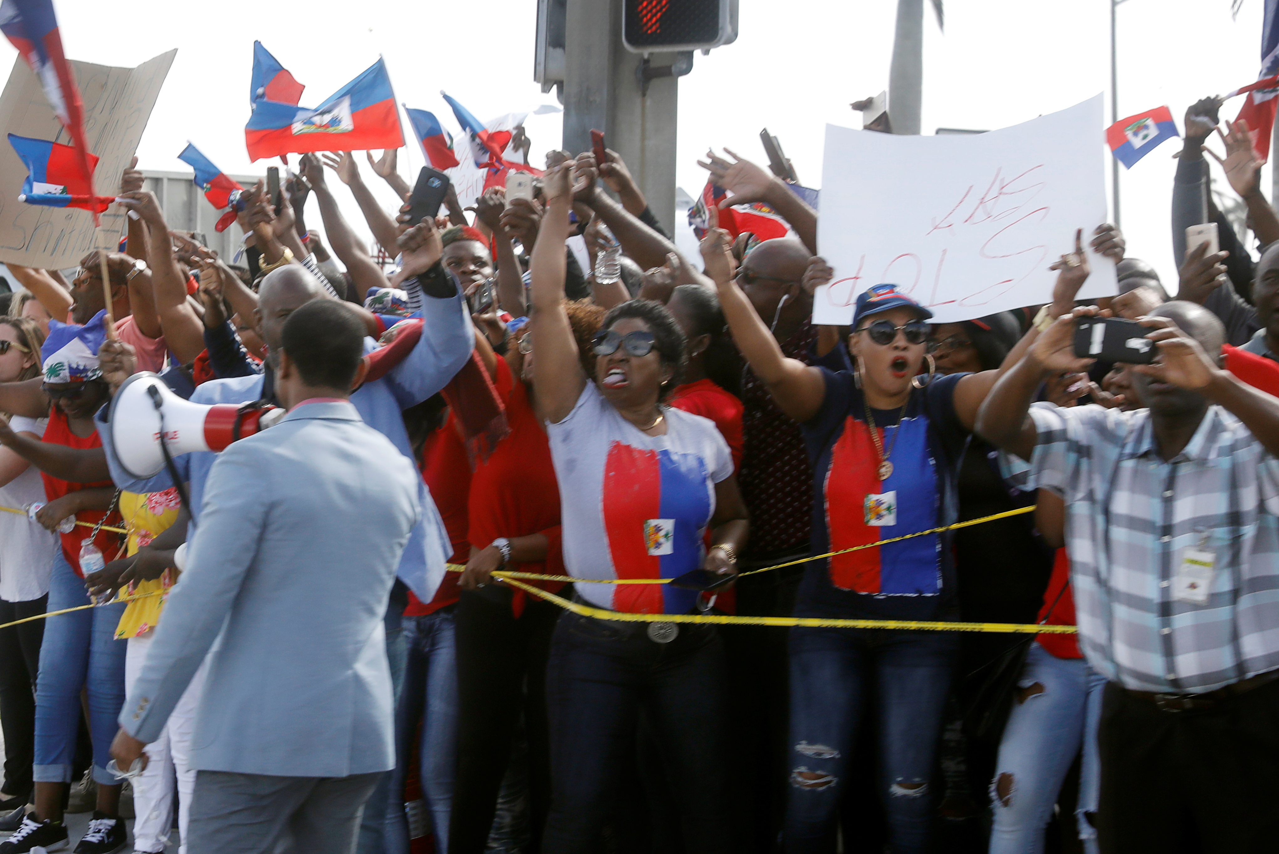 Demonstrators hold up Haitian flags and shout as the motorcade of US President Donald Trump passes in West Palm Beach, Florida, US, January 15, 2018. Credit: Reuters/Kevin Lamarque
