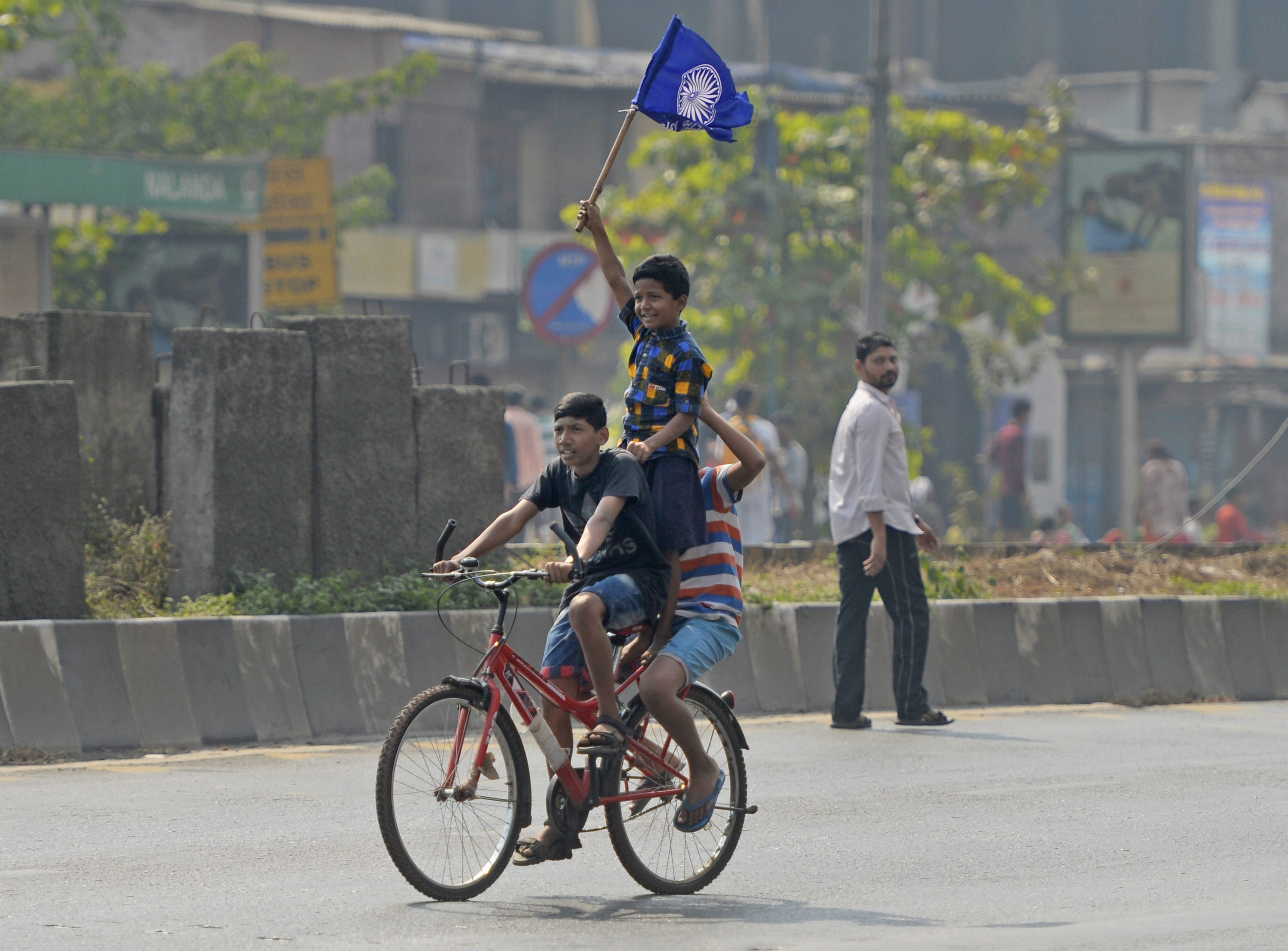 Boys carry a flag while riding a bicycle across a deserted road after Dalits called for Maharashtra bandh to protest the Bhima Koregaon violence, in Mumbai on Wednesday. Credit: PTI/Shashank Parade