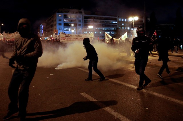 Hooded protesters stand next to teargas smoke as they clash with riot police during a demonstration against planned government reforms that will restrict workers rights to strike in Athens, Greece, January 15, 2018. Credit: Reuters/Alkis Konstantinidis