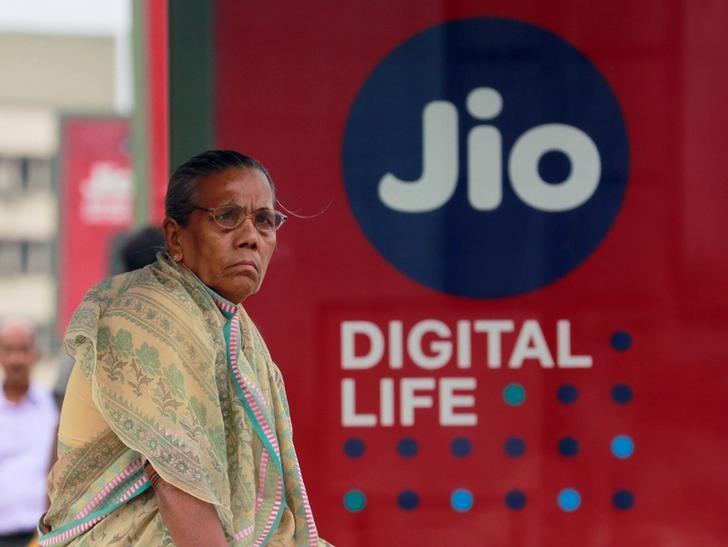 A woman waits at a bus stop with an advertisement of Reliance Industries' Jio telecoms unit in Mumbai, July 11, 2017. Credit: Reuters/Danish Siddiqui