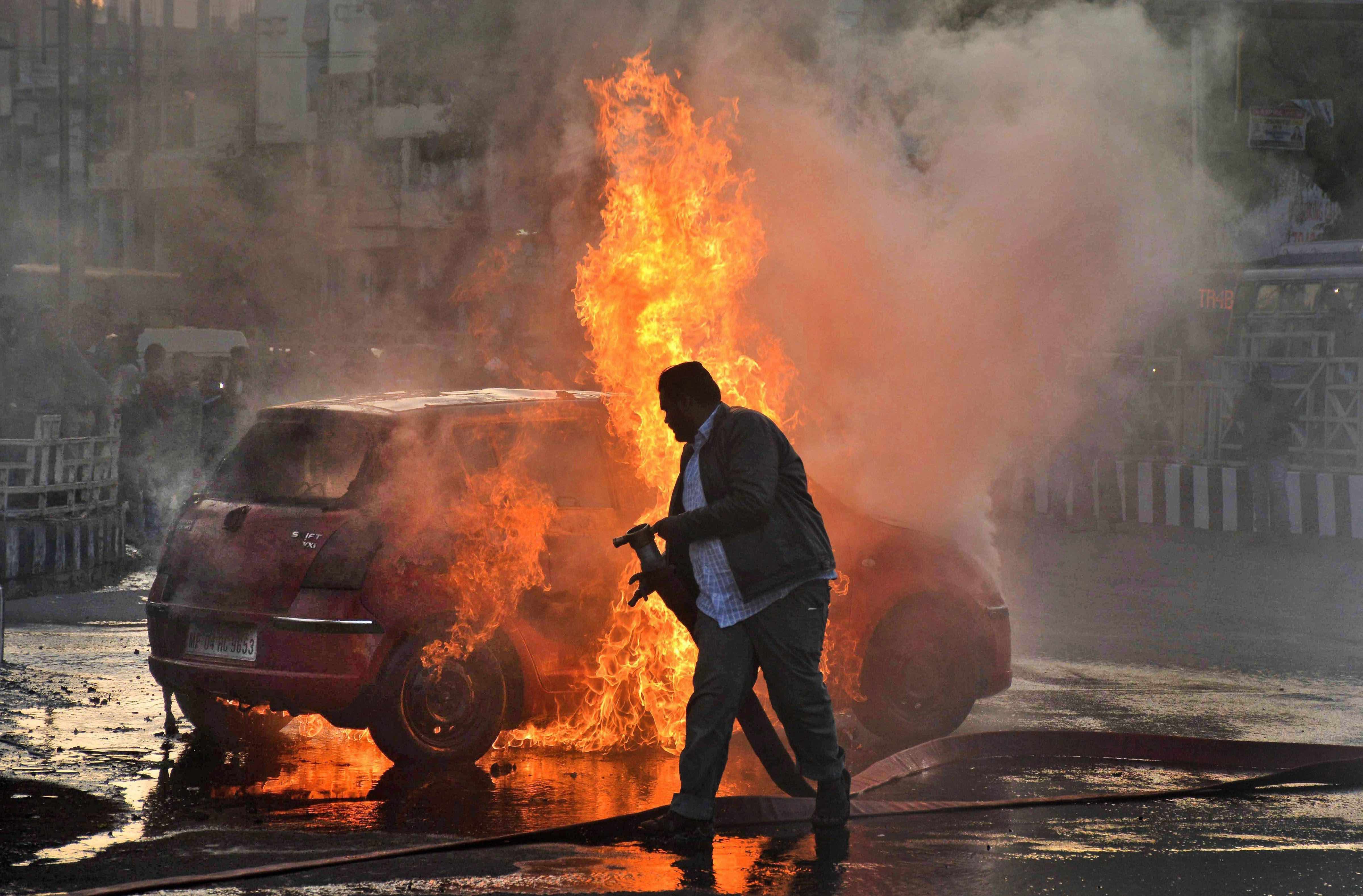 A firefighter tries to douse flames after Karni Sena activists torched a car during a demonstration against the release of 'Padmaavat' in Bhopal on Wednesday. Credit: PTI