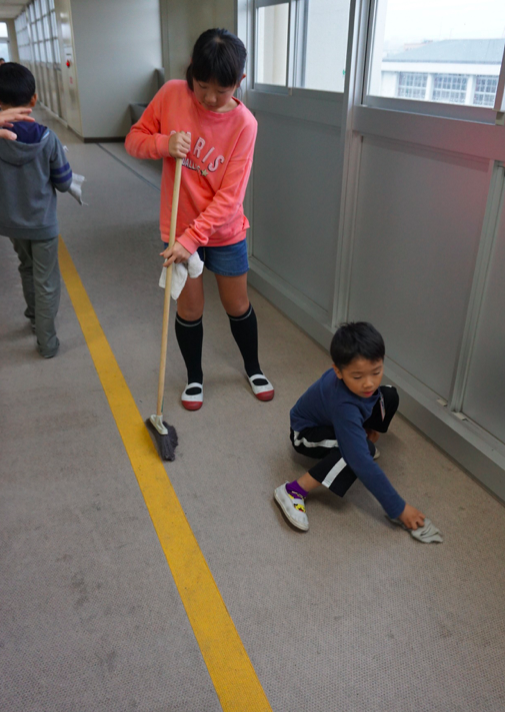 Grade VI and I students paired to clean a corridor. Credit: Janaki Nair